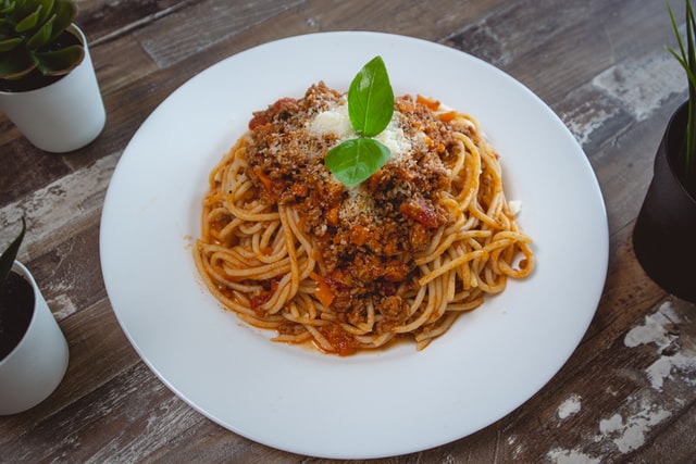 En spaghetti alla bolognese-rett i en dyp tallerken på et trebord